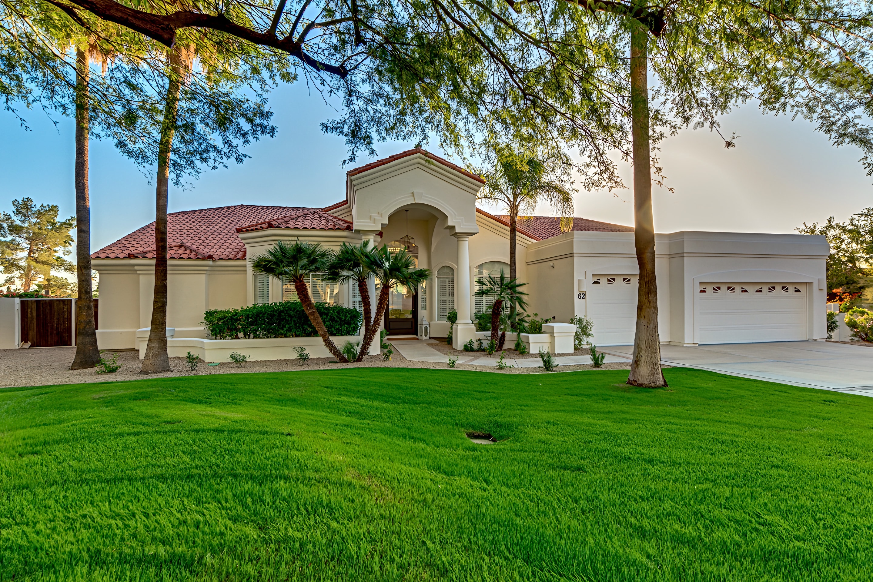 A Spanish-style Arizona home with a thick green lawn and tall palms